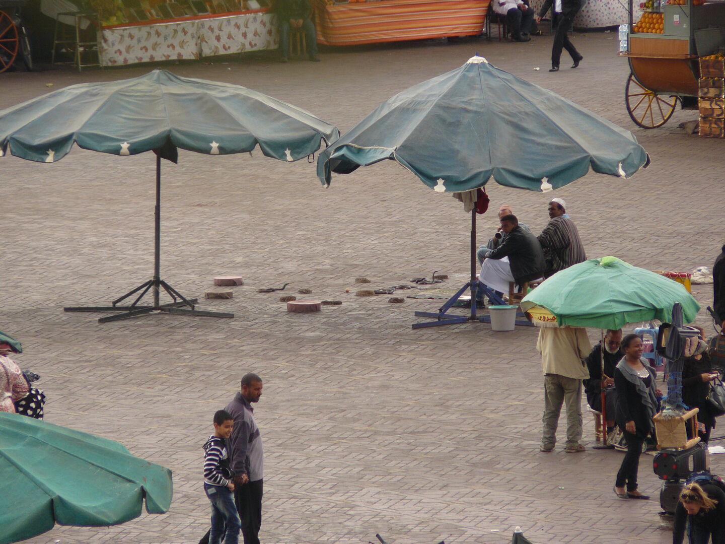 Blick auf den Platz Djeema al Fna mit Schlangenbeschwörern, Obstständen und Hennah-Frauen.