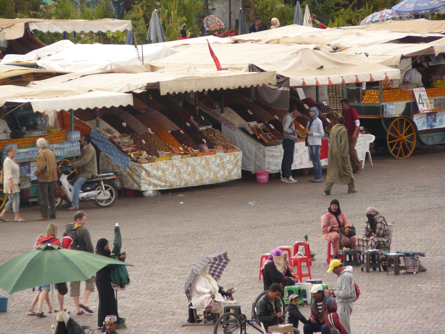 Blick auf den Platz Djeema al Fna mit Schlangenbeschwörern, Obstständen und Hennah-Frauen.