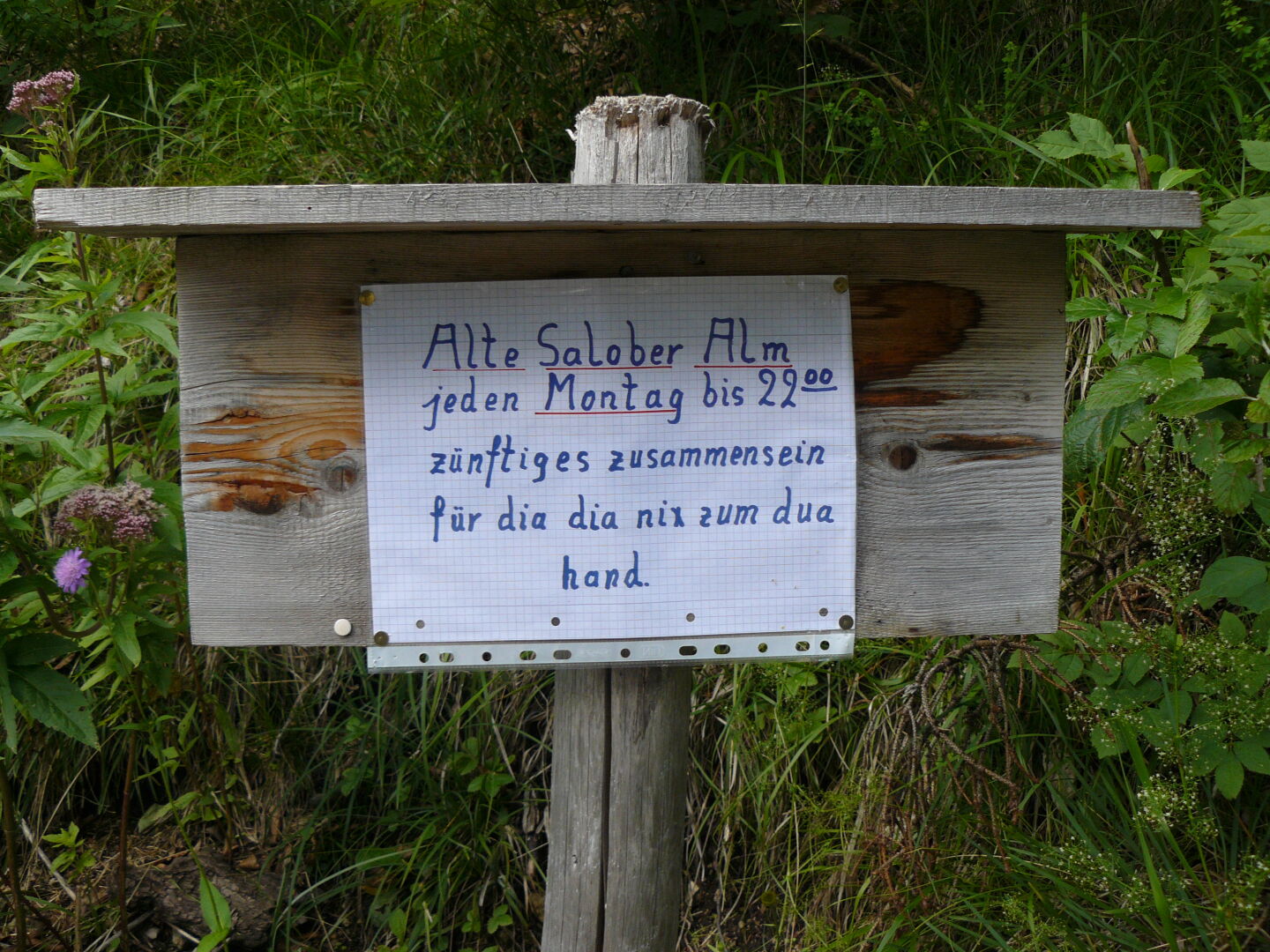 The sign reads &quot;Old Salober Alp (=name of the hut), every Monday until 10 p.m. traditional get-together for people who have nothing to do&quot;, written in Bavarian dialect.