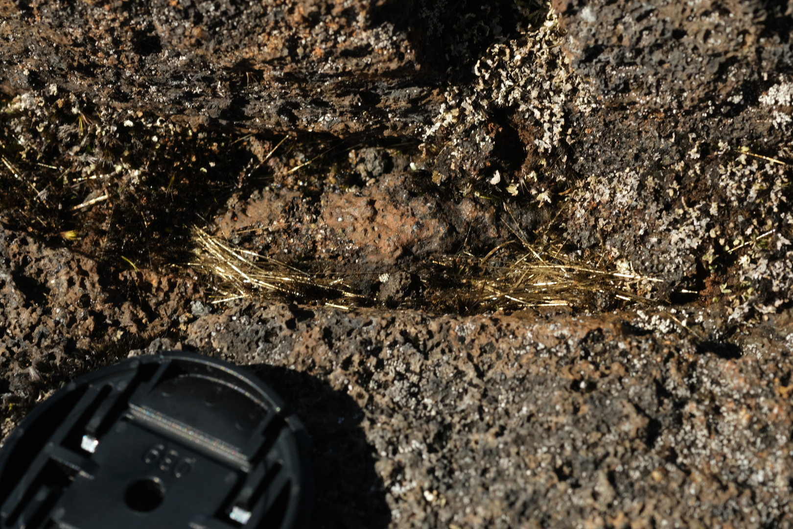 Verschiedene Arten Lava: vorne die Pahoehoe-Lava mit glatter Oberfläche, hinten die raue A-a-Lava. Die Goldfäden heißen Pele-Haar und sind aus Glas. 