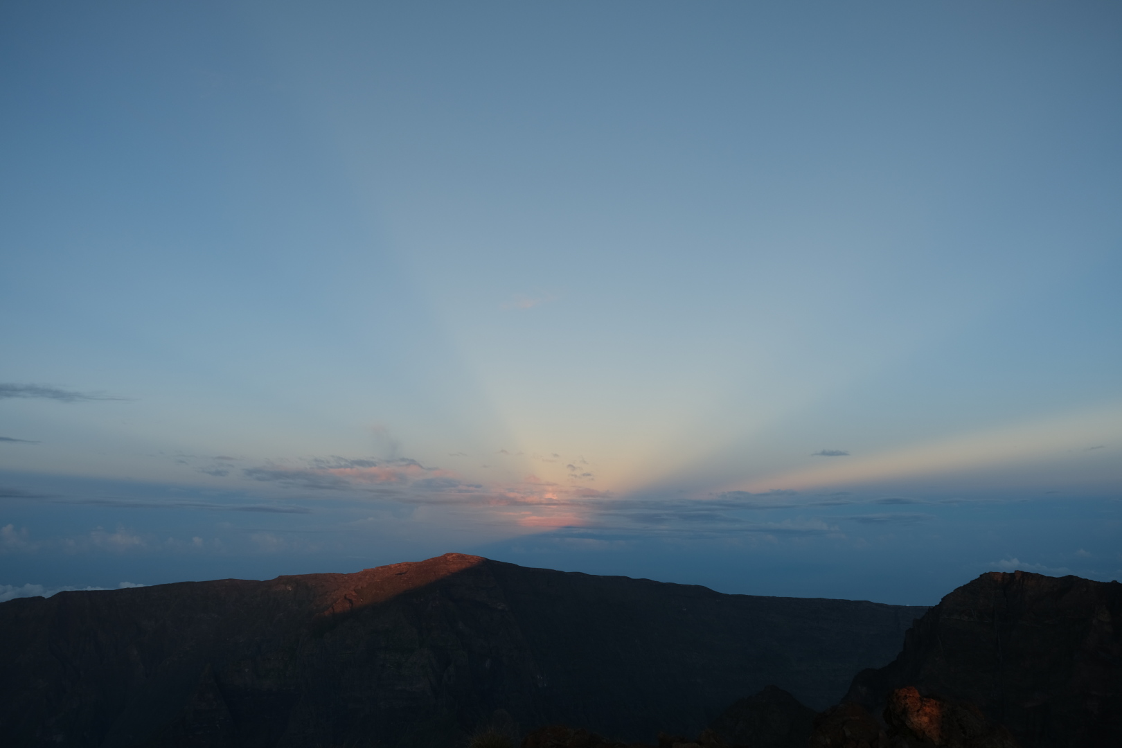 Gegendämmerungsstrahlen (anticrepuscular rays) über dem Grand-Bénare, La Réunion, bei Sonnenaufgang, vom Piton des Neiges aus gesehen.
